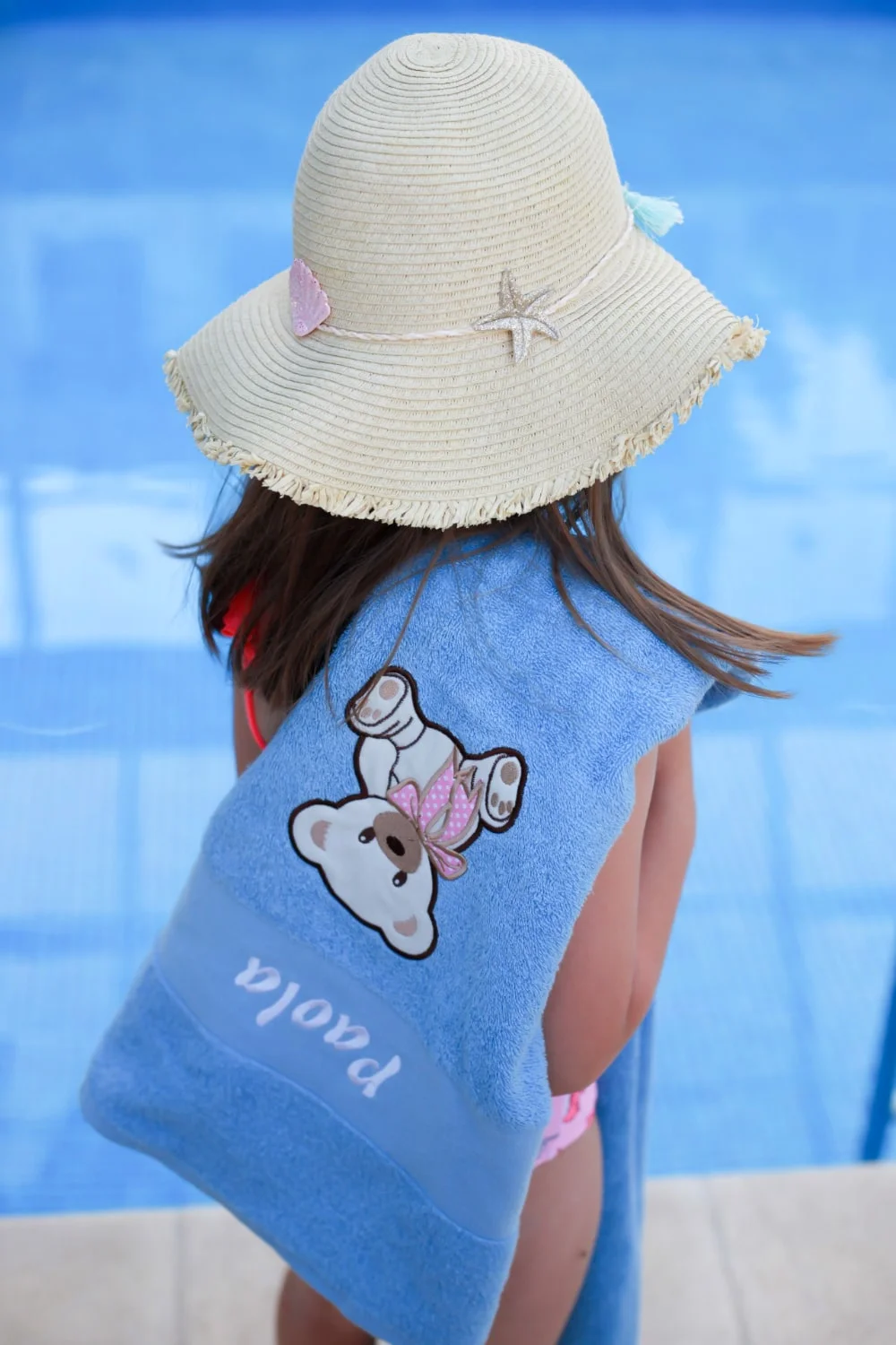 Djevojčica s ponosom pokazuje svoj personalizirani ručnik, s živopisnim dizajnom i svojim imenom.